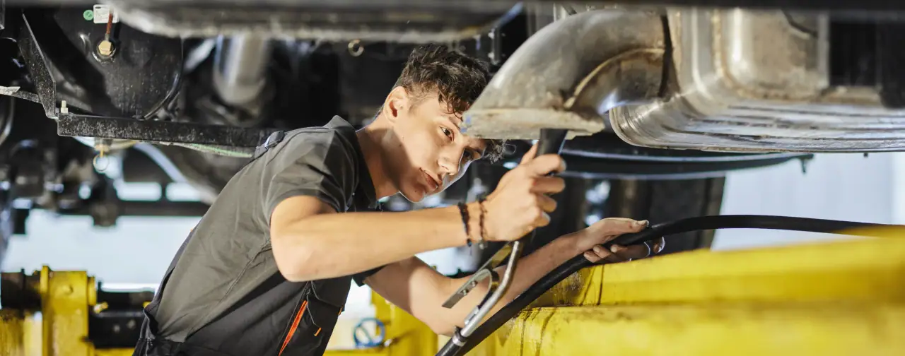 Mechanik kontroluje výfukový systém vozidla